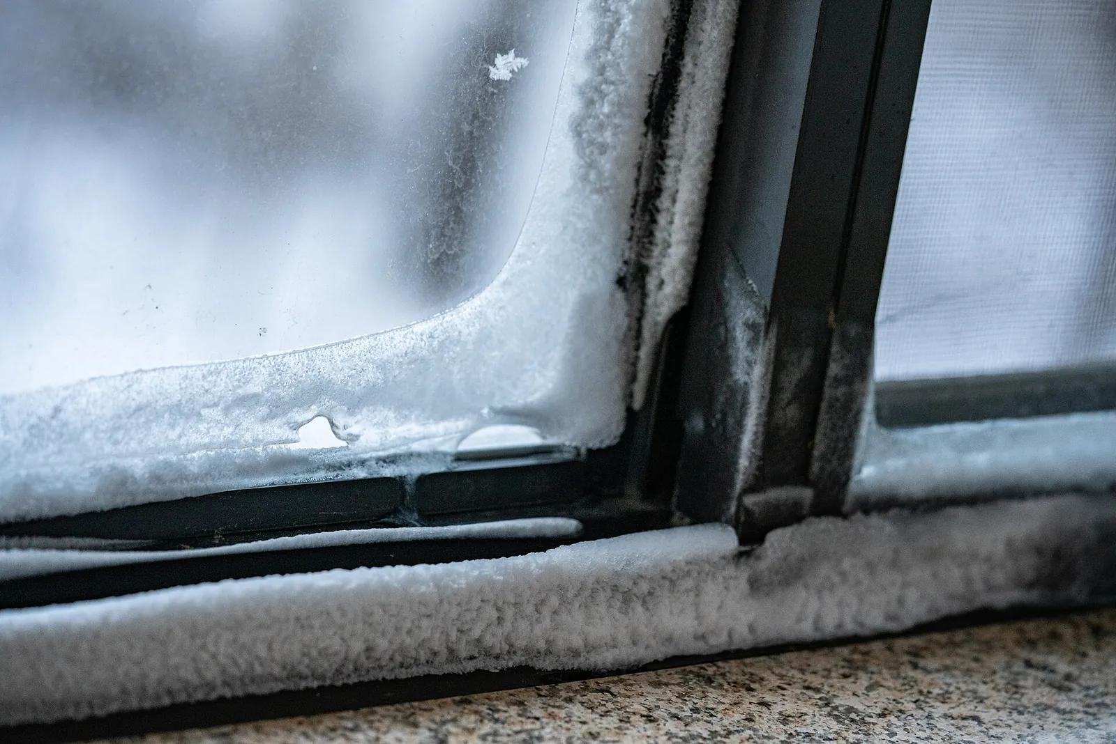 Frost and ice built up along the inside corner of a window frame